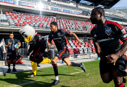 DC United Soccer player kicking ball with eagle mascot