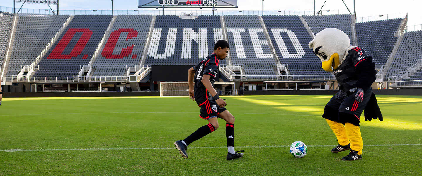 DC United player kicking ball with eagle mascot