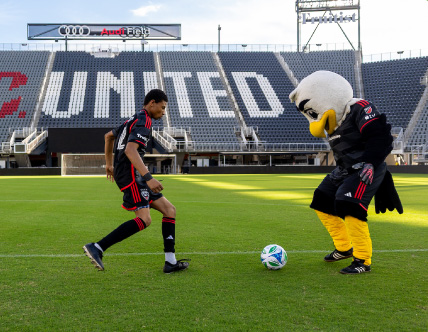 DC United Soccer player kicking ball with eagle mascot