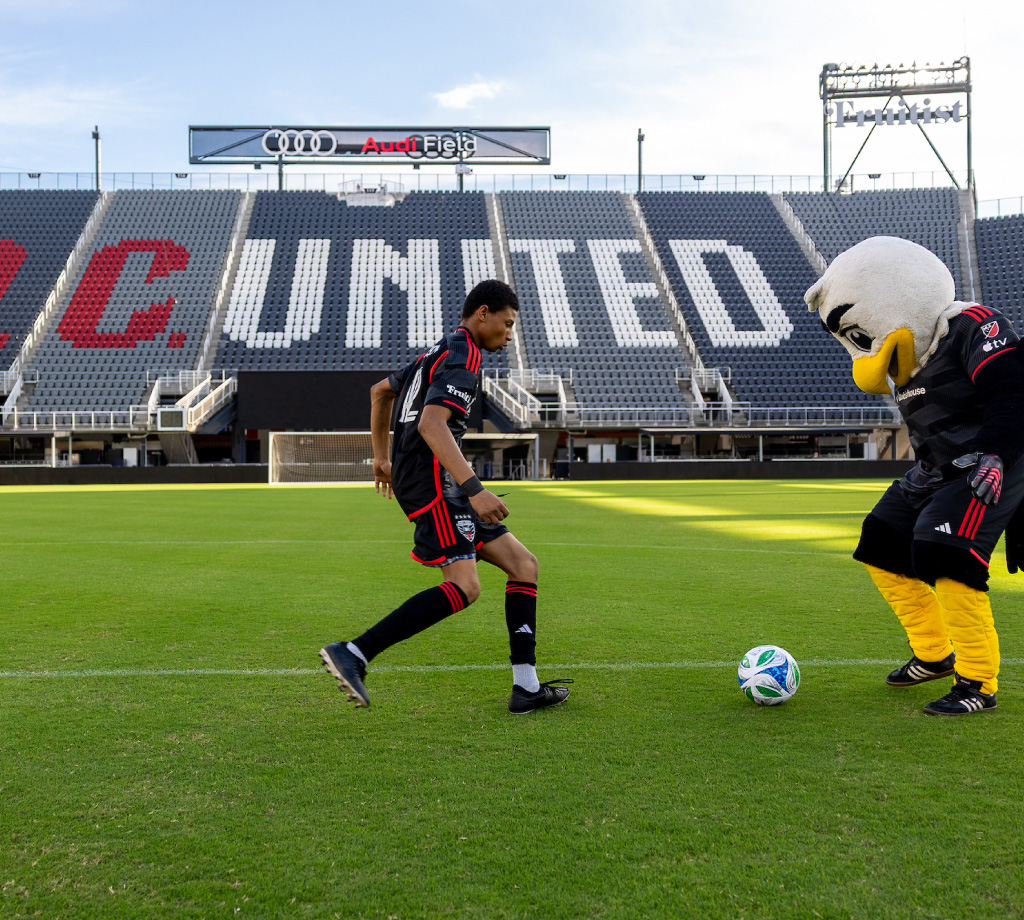 DC United Soccer player kicking ball with eagle mascot