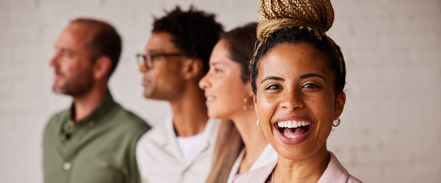 Woman looking at camera with huge smile and three people behind her