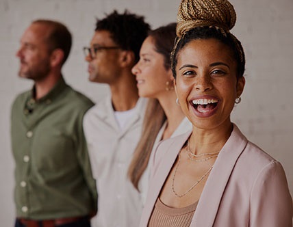 Woman looking at camera with huge smile and three people behind her