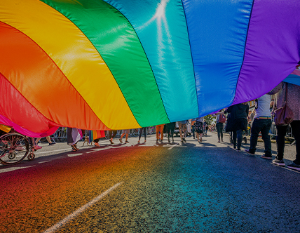 People holding rainbow flag marching in a parade