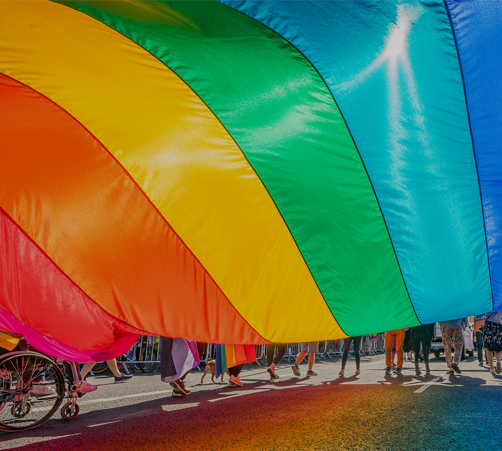 People holding rainbow flag marching in a parade