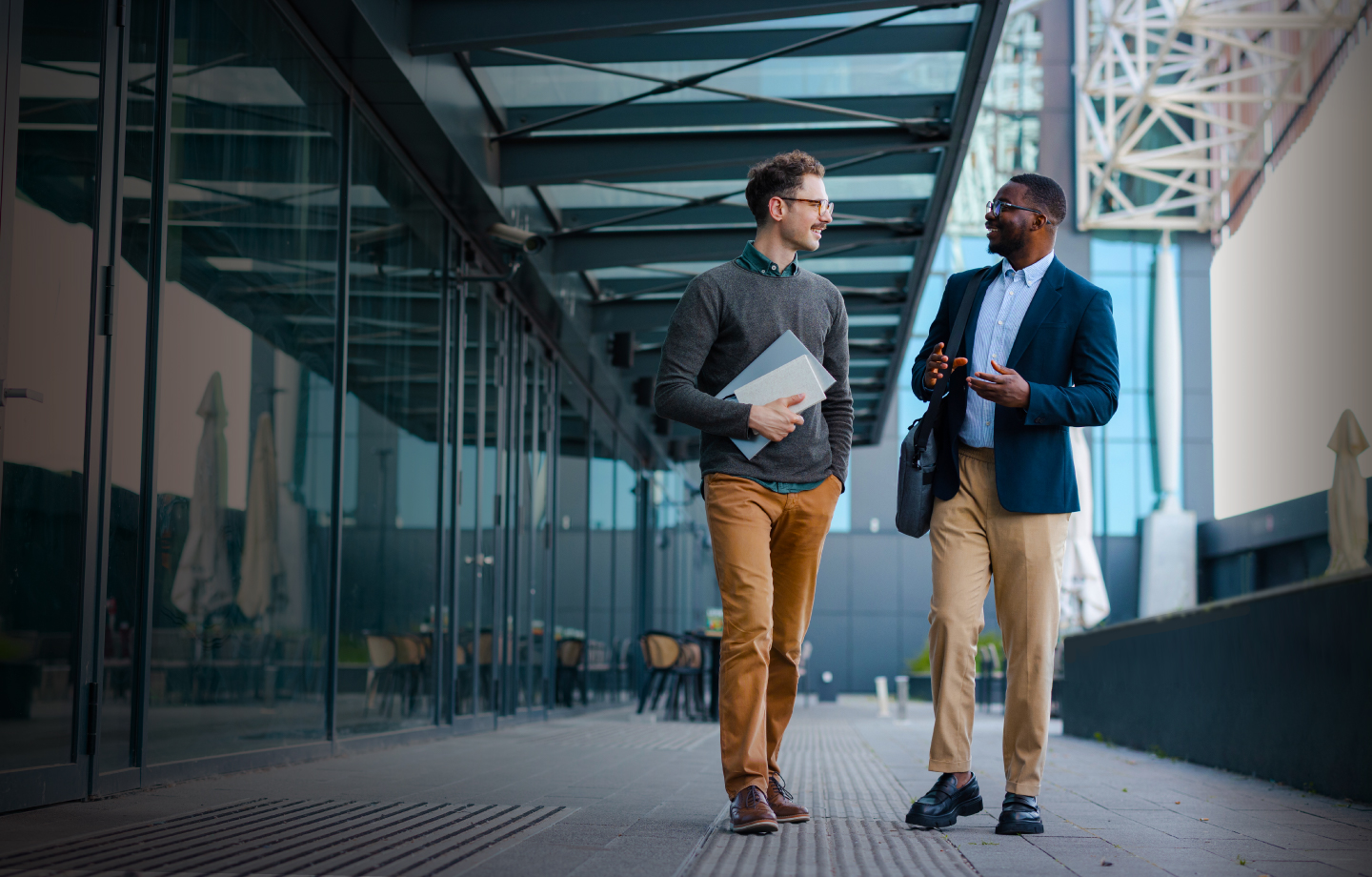 Two gentlemen walking and discussing outside a building 