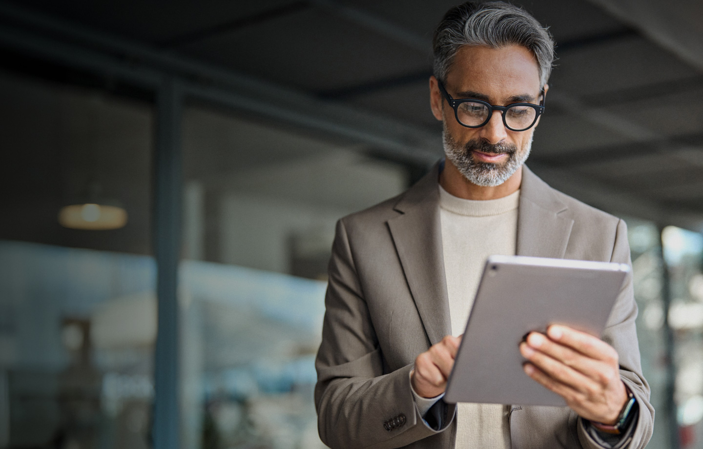 individual in the gray suit holding a tablet in the office