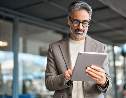 individual in the gray suit holding a tablet in the office