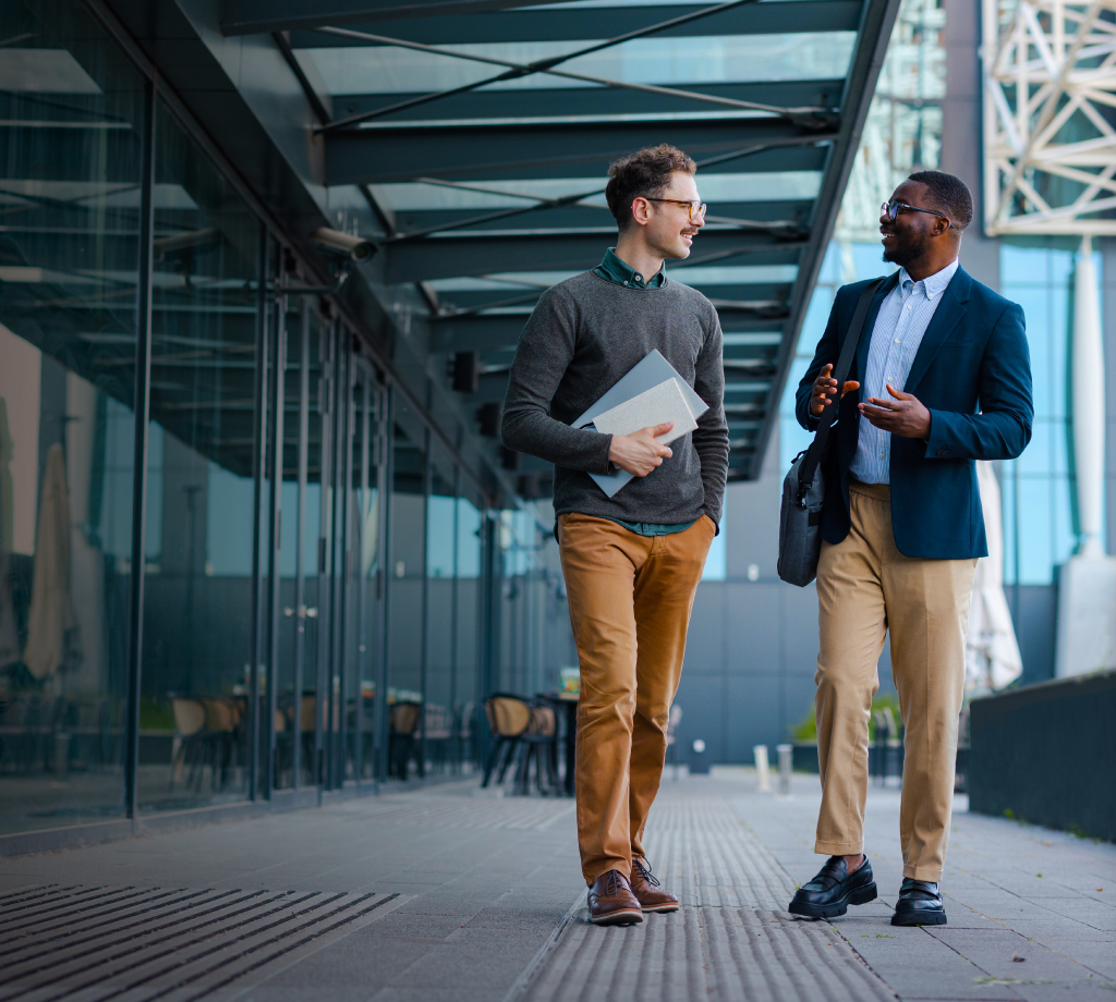 Two gentlemen walking and discussing outside a building 