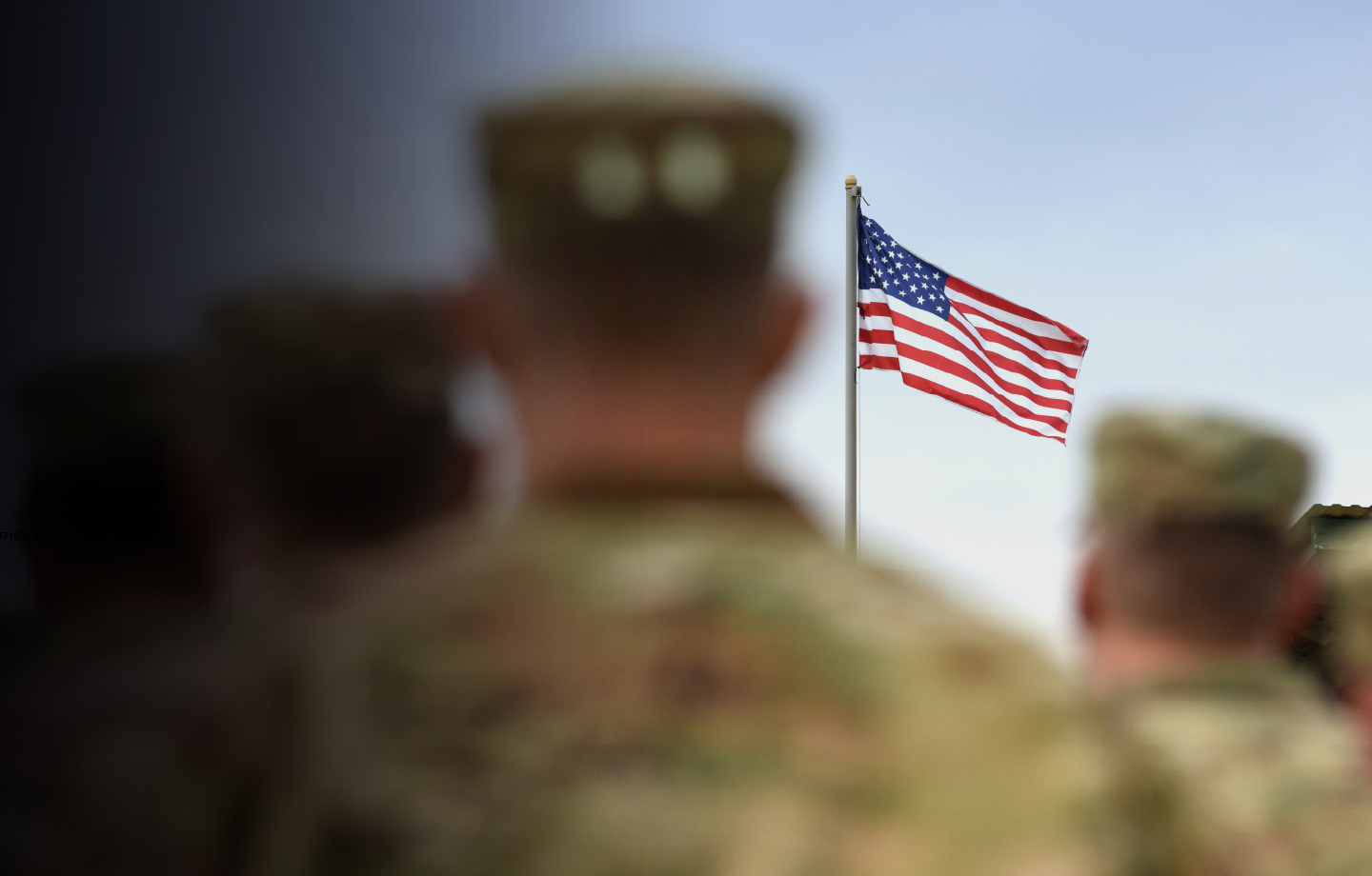 Military men in uniform looking at U.S. Flag