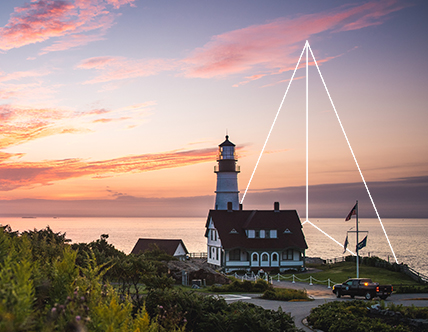 Lighthouse by cliff at sunset