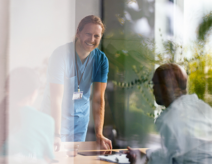 Healthcare working in blue scrubs smiling in meeting