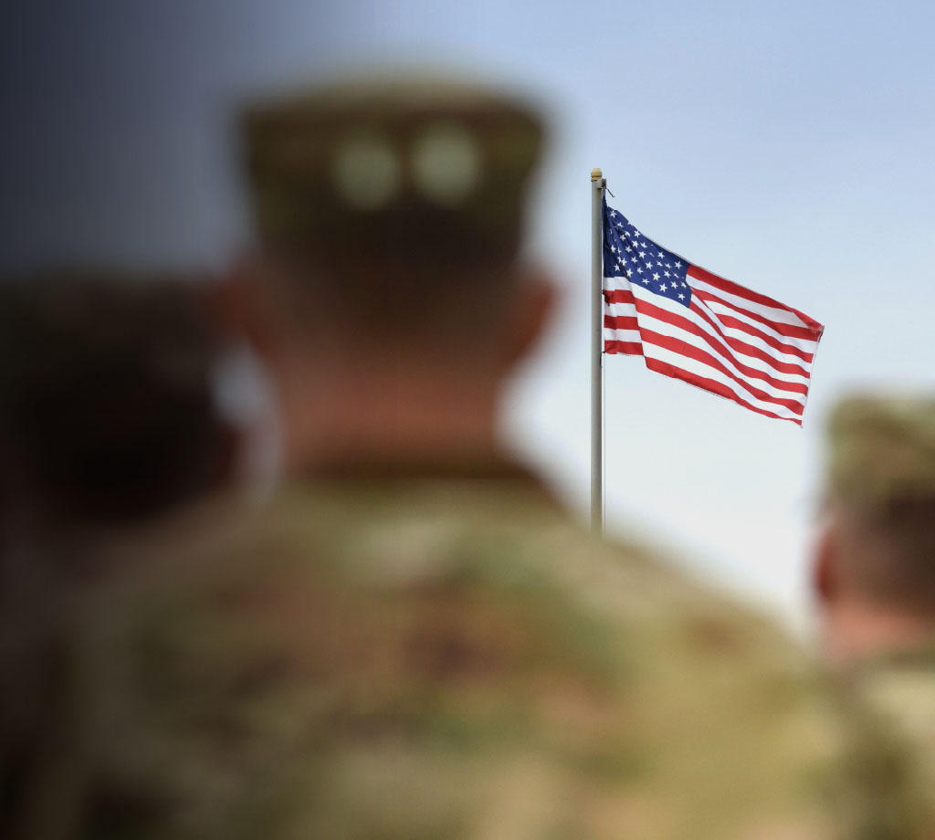 Military men in uniform looking at U.S. Flag