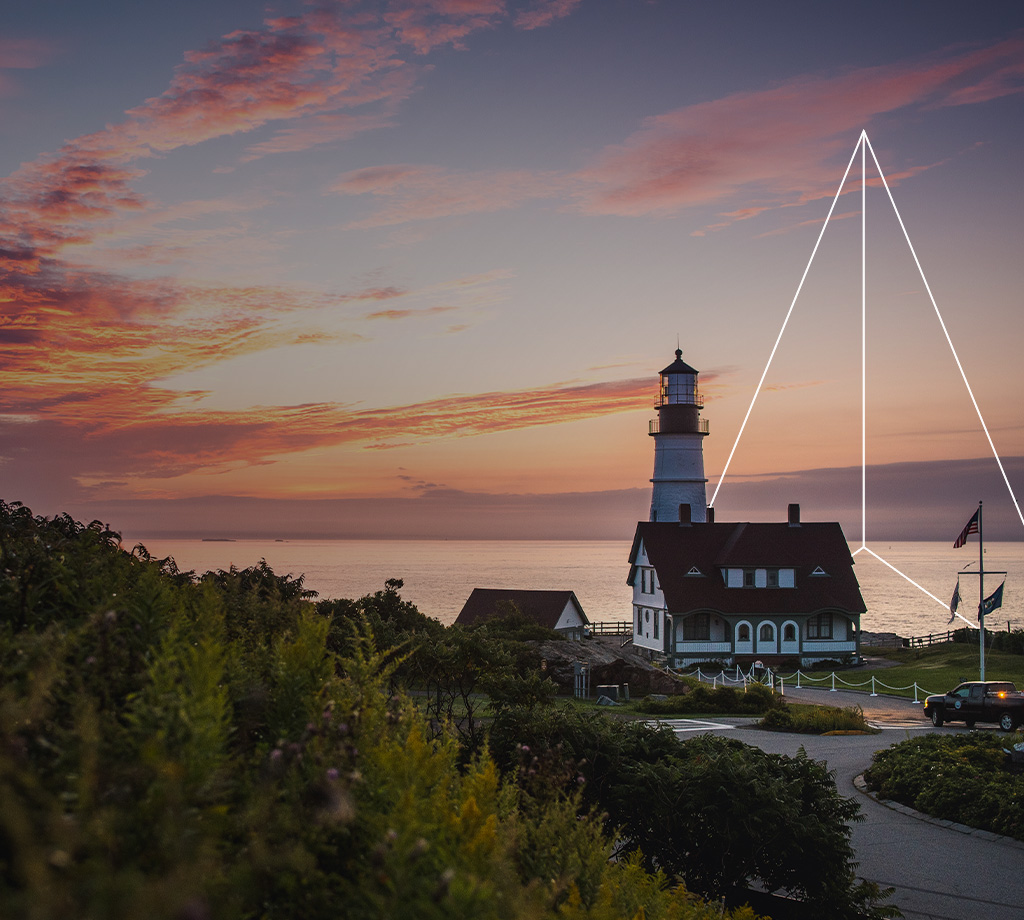 Lighthouse by cliff at sunset