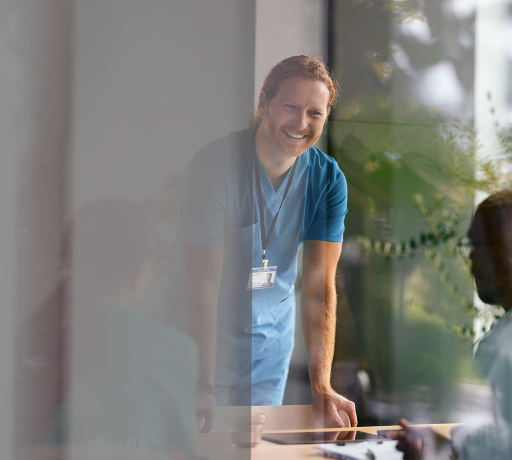 Healthcare working in blue scrubs smiling in meeting