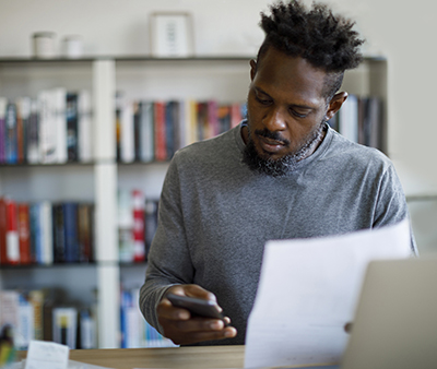 Man looking at phone and paper