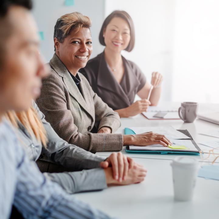 women attending meeting with multiracial group of colleagues in creative office interior