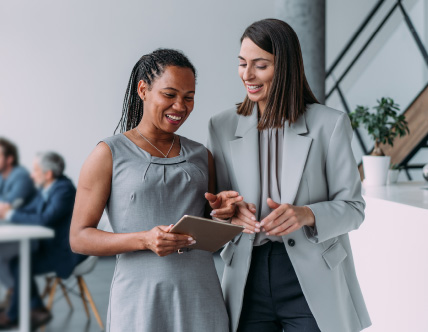 two women looking at tablet in conference room