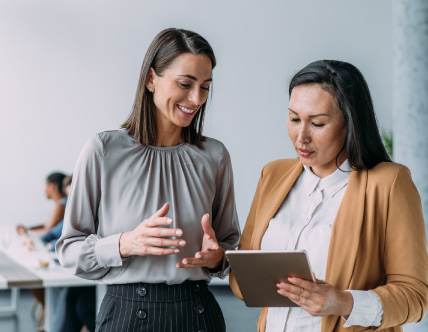 two women looking at tablet in conference room