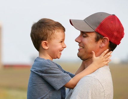 Young farmer dad holding son