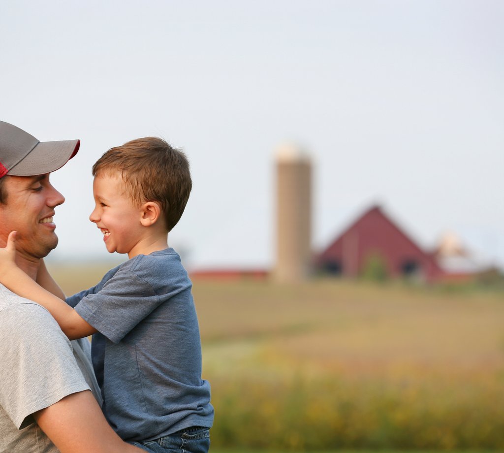Young farmer dad holding son