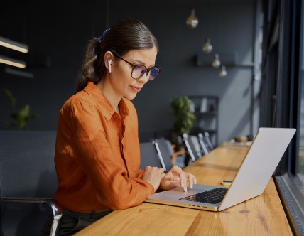 Woman at laptop with orange shirt